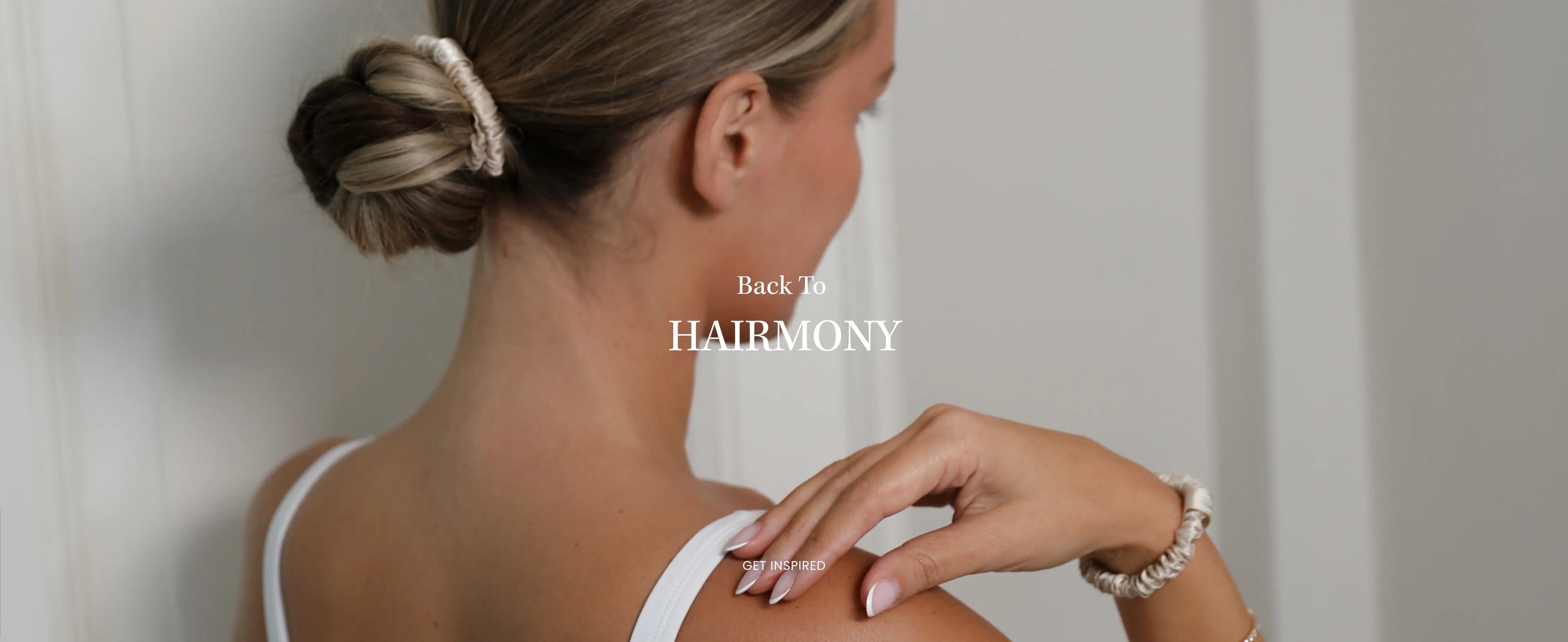 Woman with blonde hair in a low bun wearing a Mulberry Silk Skinny Scrunchie in Beige, showcasing Lenoites Back to Hairmony launch.